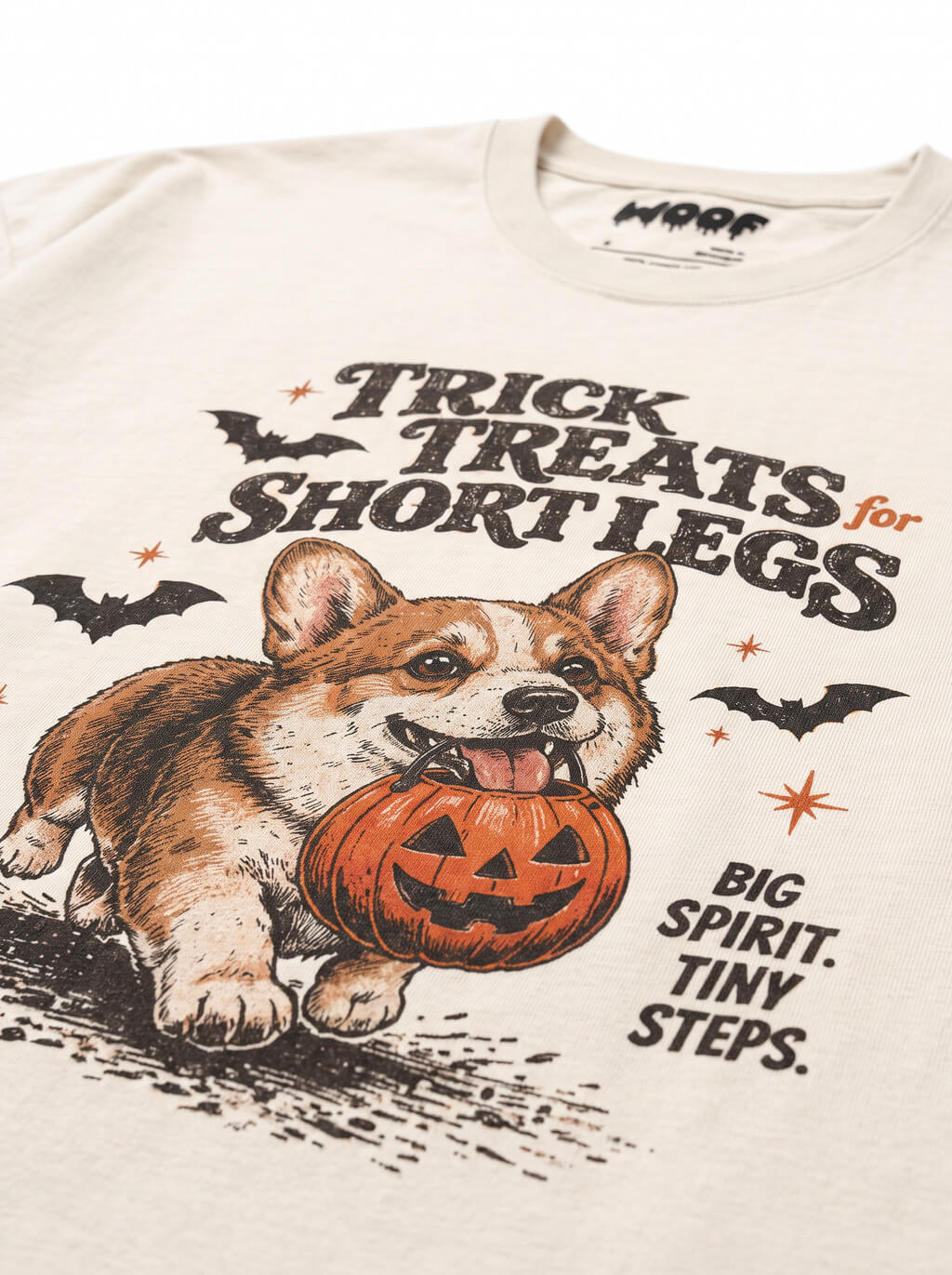 Close-up of the "Trick Treats for Short Legs" print with a Corgi running with a pumpkin bucket on the Vintage White tee