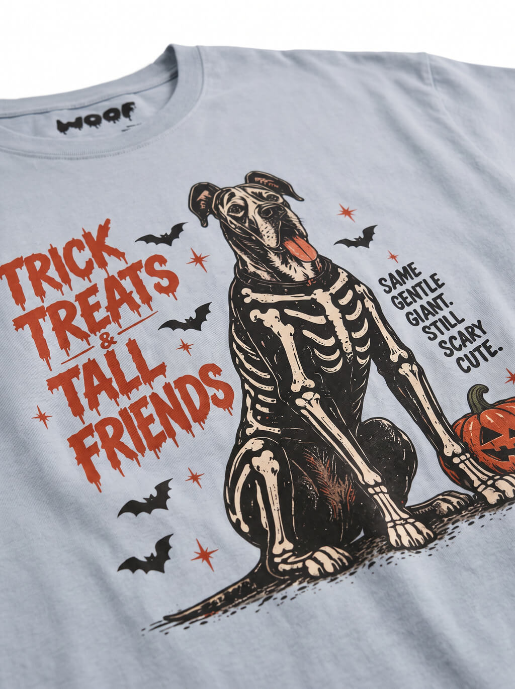 Close-up of the "Trick, Treats & Tall Friends" print with a skeleton Great Dane with a pumpkin bucket on the Light Washed Denim tee