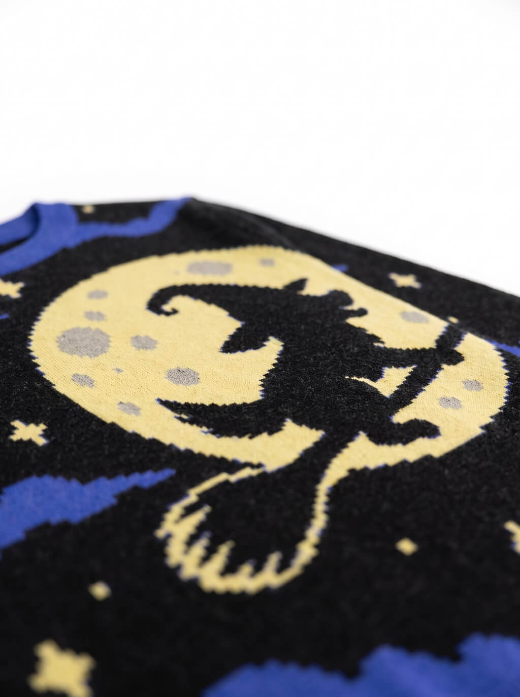 Close-up of the knitted witch and full moon motif on the black and blue Halloween sweater